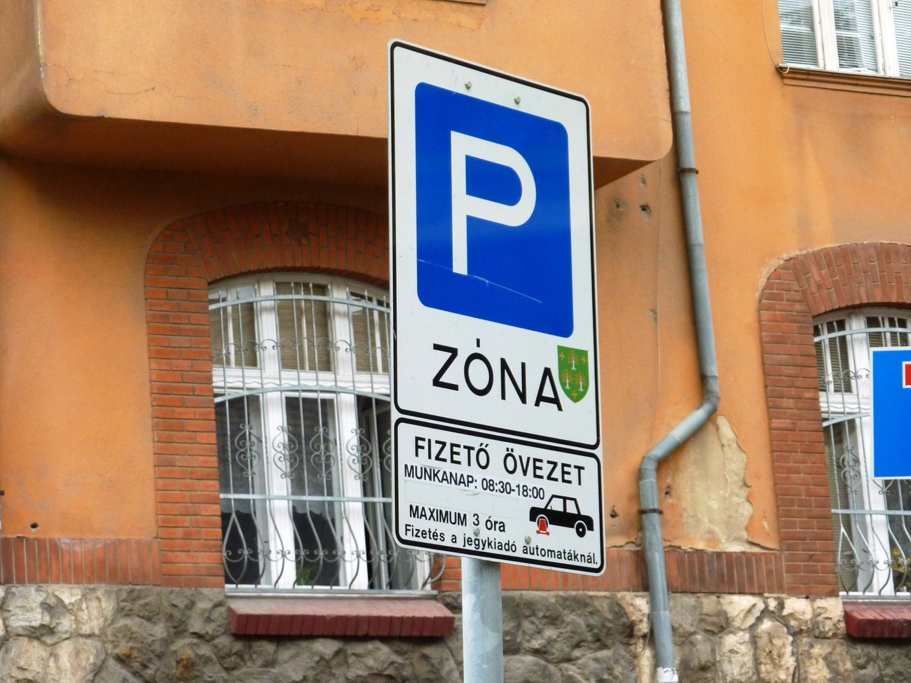 A tábla azt jelzi, hogy az úton a várakozás (parkolás) megengedett